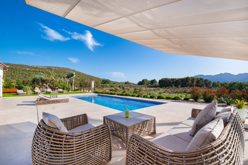 Conjunto de muebles de exterior de lujo en la terraza de una villa en Bernia, con un sofá modular y tumbonas junto a la piscina.