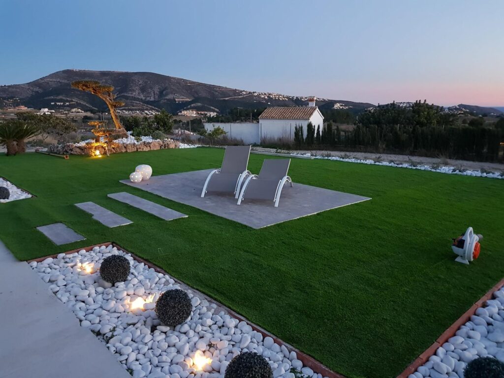 Jardín de lujo terminado por Luxury Garden Center al atardecer, con dos modernas sillas como punto focal.